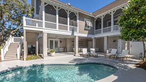 Une maison à deux étages avec une piscine, un espace salon extérieur et un patio couvert.