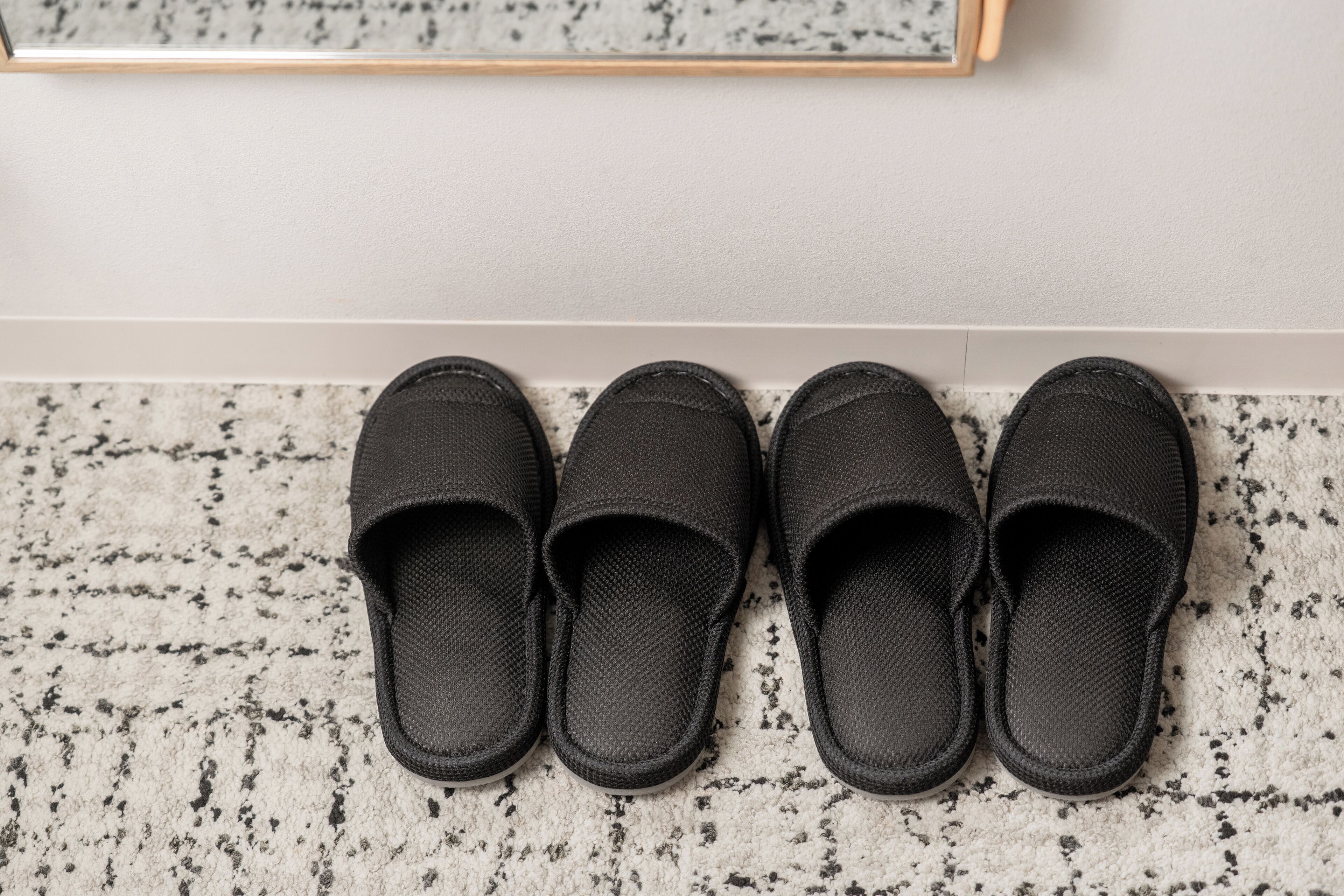 Un par de zapatillas negras sobre una alfombra con manchas.