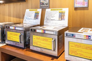 A display of Panasonic microwaves with instructions and safety warnings.