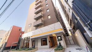 Ein mehrstöckiges Hotel mit modernem Design, das eine markante Eingangspartei mit Glasfassade, Balkone in den oberen Stockwerken und eine gut beleuchtete Außenansicht aufweist.