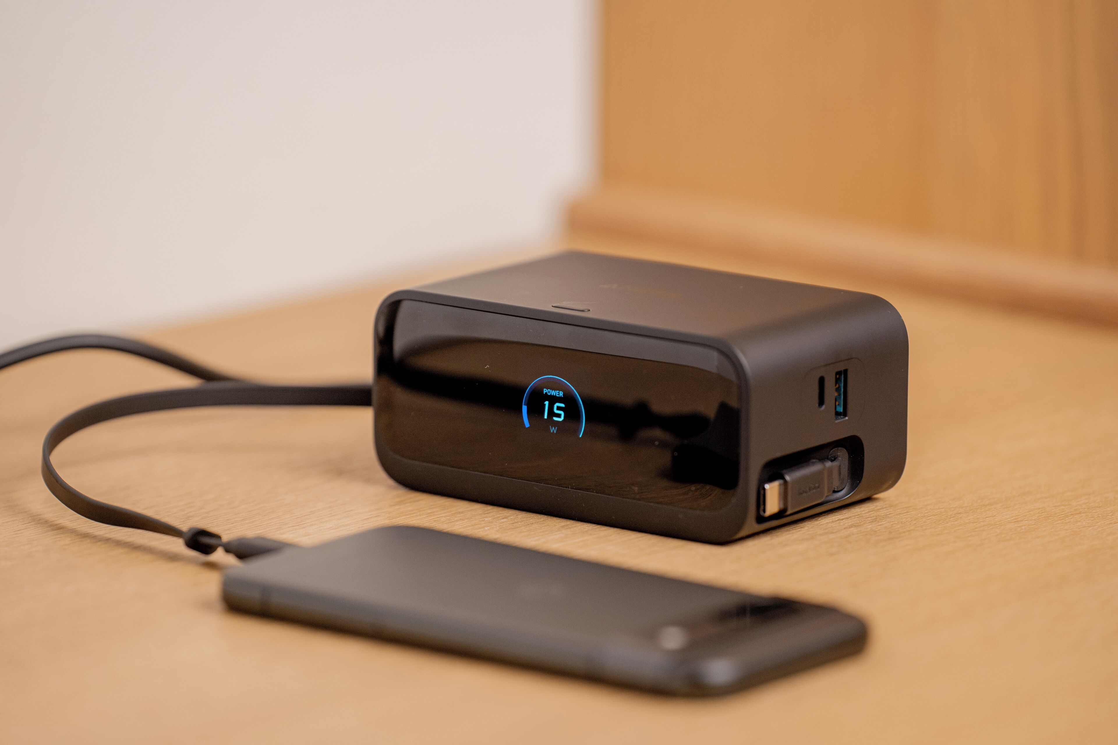 Een draagbare powerbank met een USB-poort en een display dat 15W vermogen aangeeft, aangesloten op een smartphone.