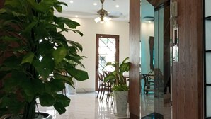 A hallway with marble flooring, potted plants, wooden paneling, and a ceiling fan. - Sentina Phu Quoc Hotel (Phu Quoc)