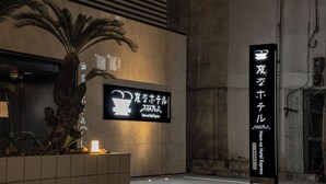 Un letrero de hotel con caracteres japoneses y una señal de neón encima.