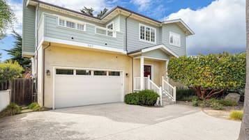 A two-story house with a garage, a red door, and a staircase leading to the front porch.