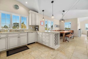 A spacious kitchen with white cabinetry, a large island, and pendant lighting. - Gorgeous Pleasure Point Home - Sleeps 10! (Santa Cruz)
