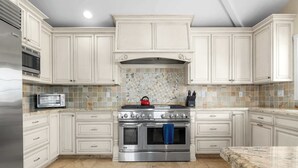 A kitchen with white cabinetry, a stainless steel stove, a microwave, and a toaster.