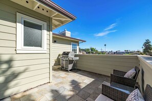 Eine Terrasse mit Grill, Korbmöbeln und Blick auf eine Stadtlandschaft.