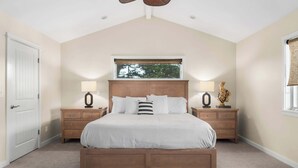 A bedroom with a large bed, two nightstands, a window with a view, and a door. - Gorgeous Pleasure Point Home - Sleeps 10! (Santa Cruz)