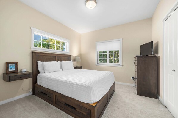 A bedroom with a bed, nightstands, a TV, and a wardrobe.