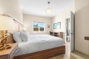 A bedroom with a bed, bedside table, lamp, and a view of the bathroom. - Gorgeous Pleasure Point Home - Sleeps 10! (Santa Cruz)