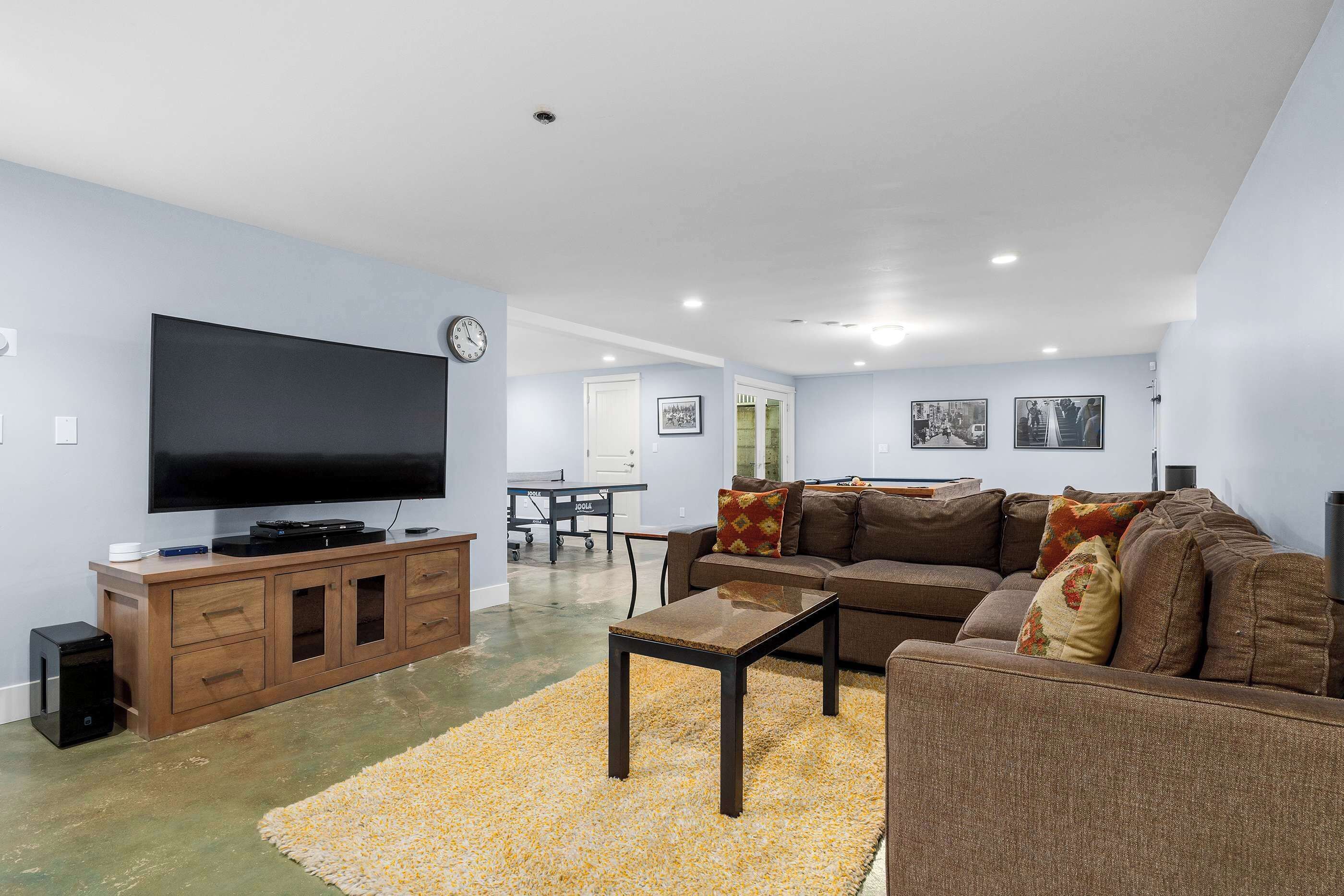 A living room with a flat-screen TV, wooden entertainment unit, brown sofa, and a coffee table.