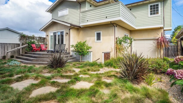 A two-story house with a front porch, a small garden, and a red chair outside. - Gorgeous Pleasure Point Home - Sleeps 10! (Santa Cruz)