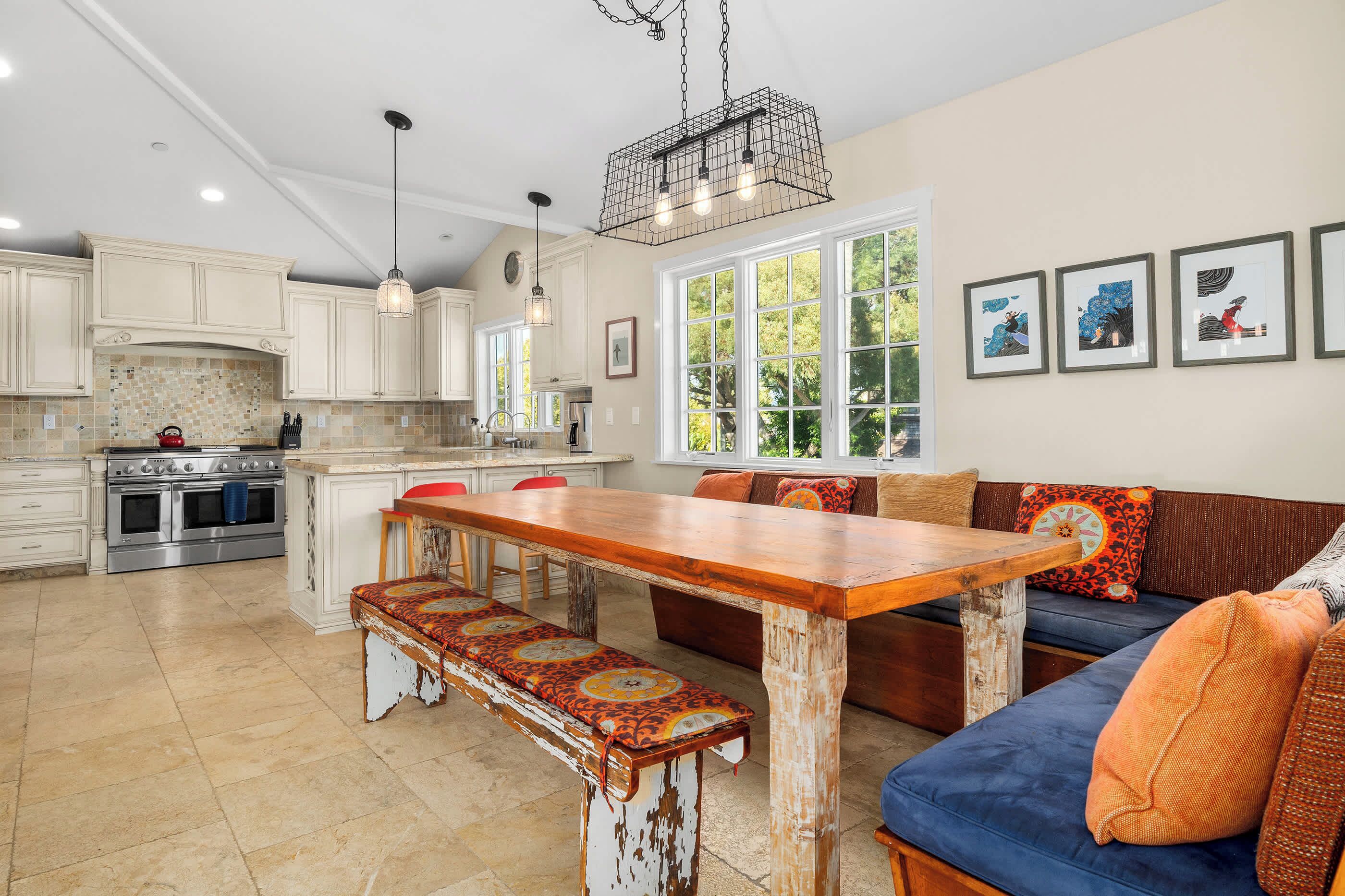 A spacious kitchen with white cabinets, a wooden dining table, and a bench.