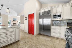 Una cocina amplia con armarios blancos, un refrigerador de acero inoxidable y un microondas.