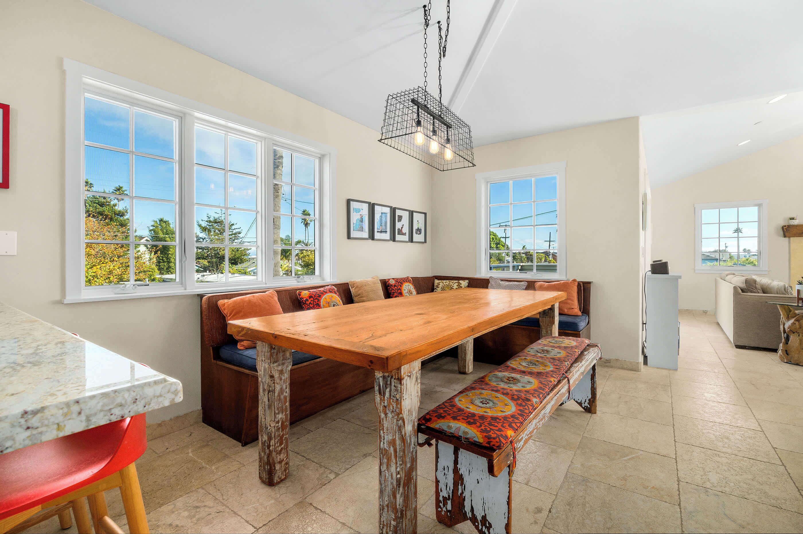 A spacious kitchen with a large wooden table, built-in bench, and a hanging light fixture.