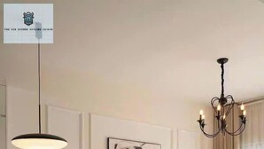 Una sala de estar moderna con un sofá blanco, una mesa de comedor con sillas, una araña y un cuadro abstracto grande en la pared.