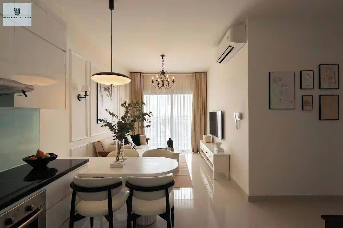 A modern kitchen with a dining area, featuring a chandelier, a flat-screen TV, and artwork on the walls.