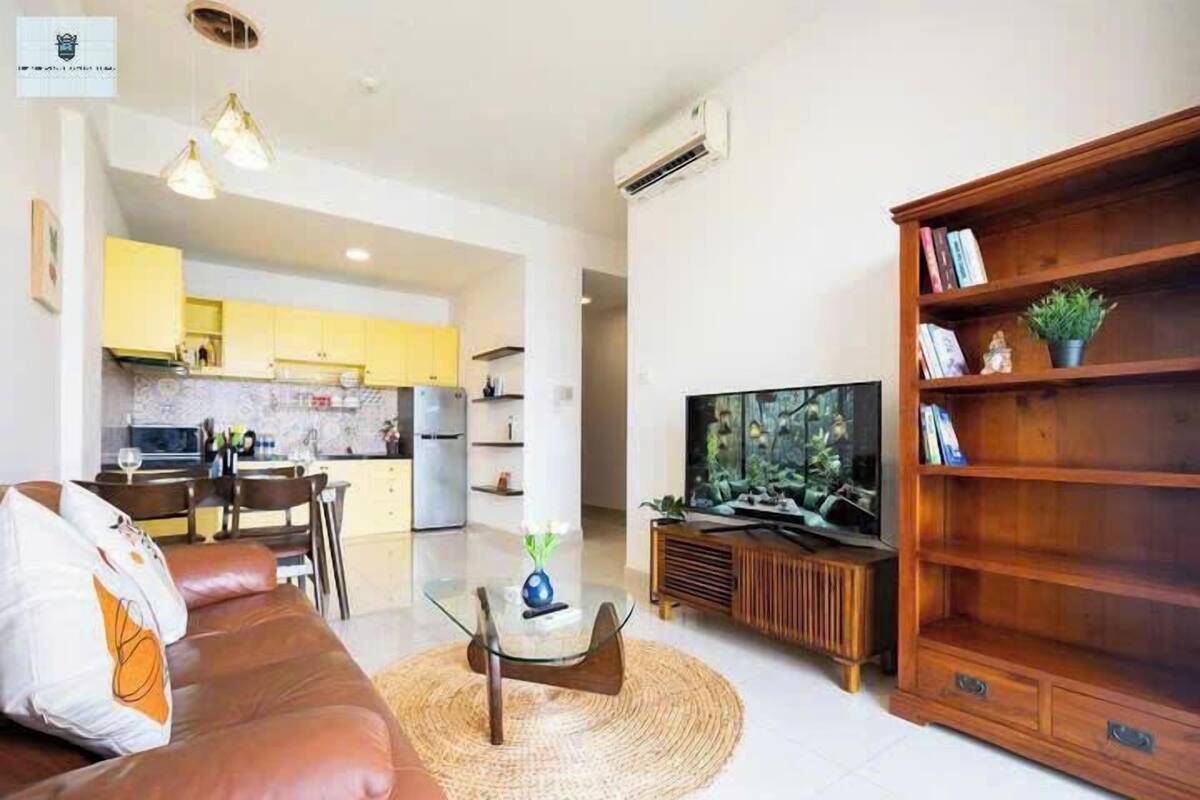 A modern living room with a brown leather sofa, a glass coffee table, and a wooden entertainment unit with a TV.