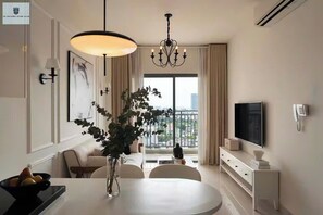 A modern hotel room with a dining area, a large window with a view, a chandelier, and a flat-screen TV. - The Sun Avenue Skyline Saigon (Ho Chi Minh City)
