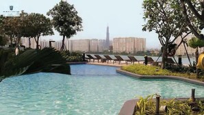 Piscina con sillas de descanso, rodeada de follaje y un paisaje urbano al fondo.