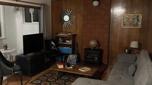 Un salon avec un canapé gris, un fauteuil noir, une table basse en bois et un téléviseur.