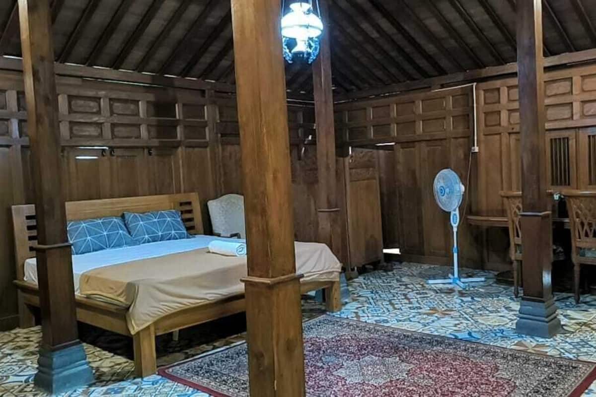 A wooden room with a bed, a fan, and a table with chairs.