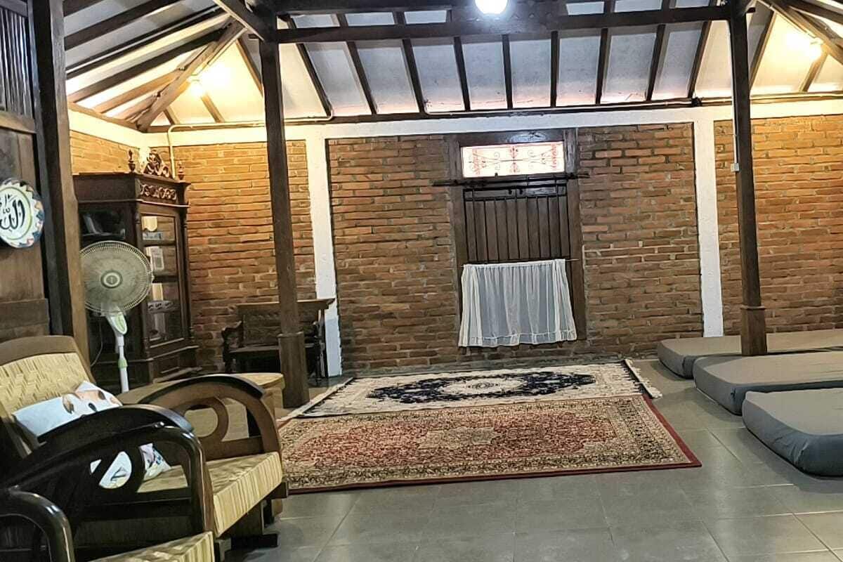 A cozy room with a brick wall, a large rug, and a ceiling fan.