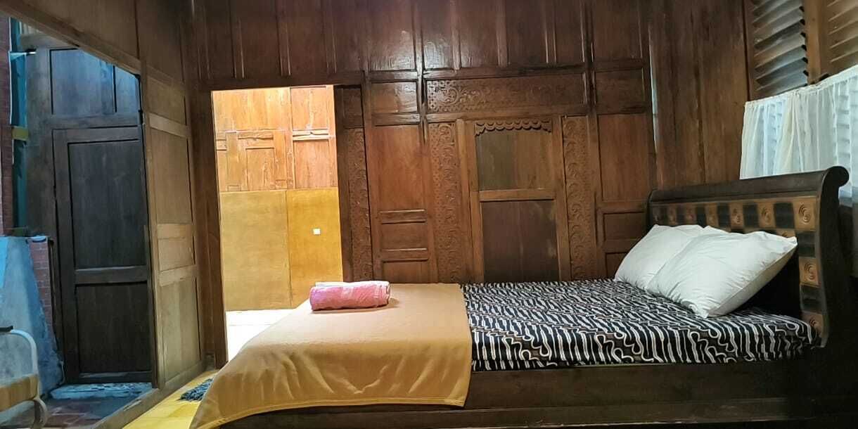 A wooden room with a bed, a door, and a window.