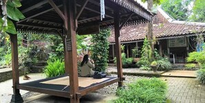 A wooden gazebo with a bench, surrounded by lush greenery and a tiled roof structure. - Ndalem Pengkok Homestay (Patuk)