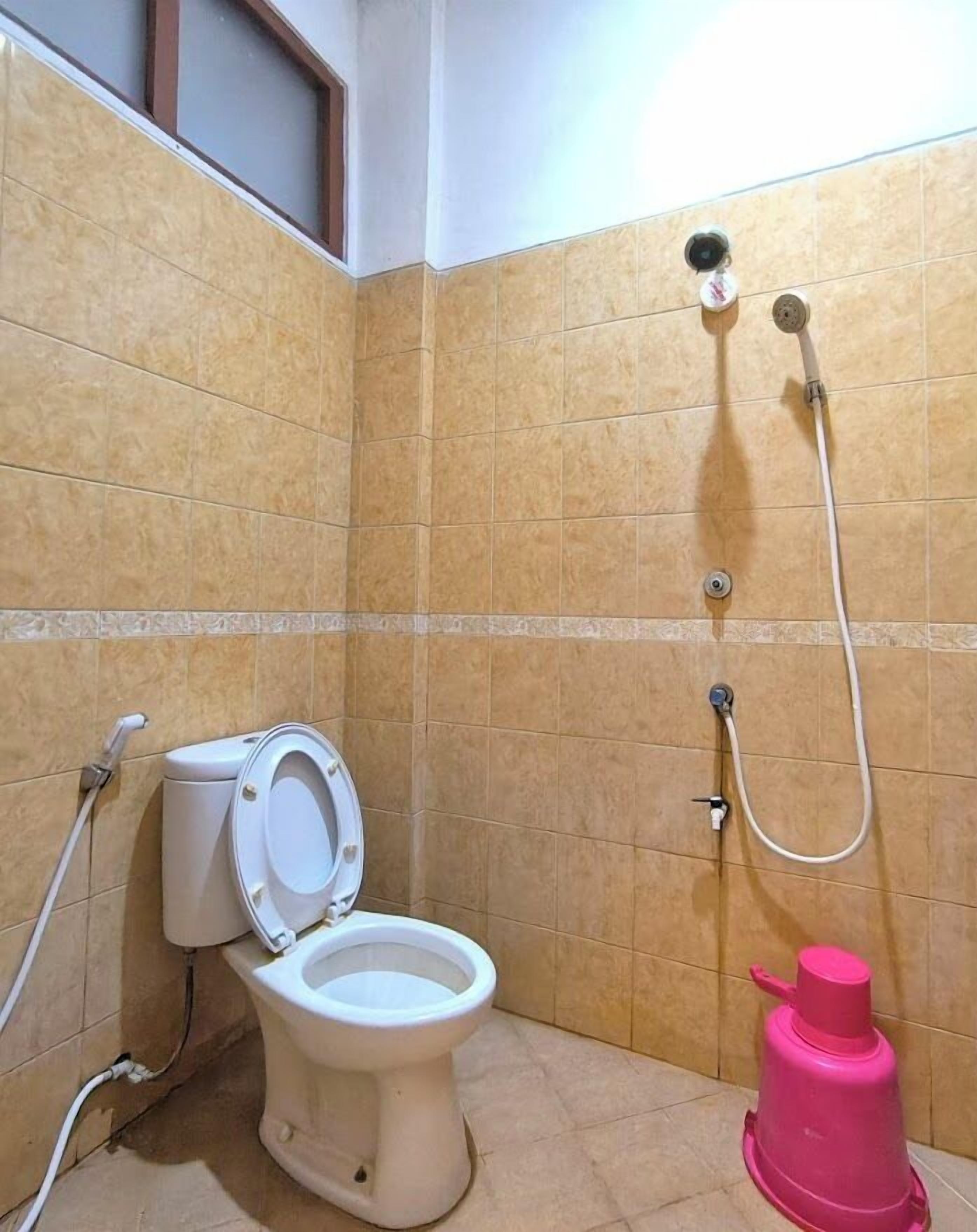 Un baño con inodoro, ducha y un bidé rosa.