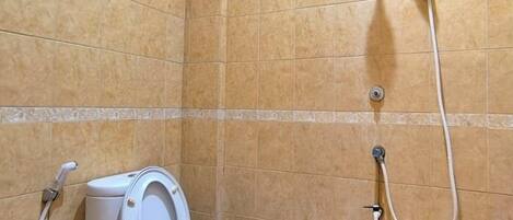 Un baño con inodoro, ducha y un bidé rosa.