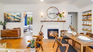Ein modernes Wohnzimmer mit Kamin, Holzmöbeln und einem Essbereich.