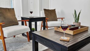 A modern living room with a dark wooden coffee table, a glass of red wine, and a tray with books and a small plant.