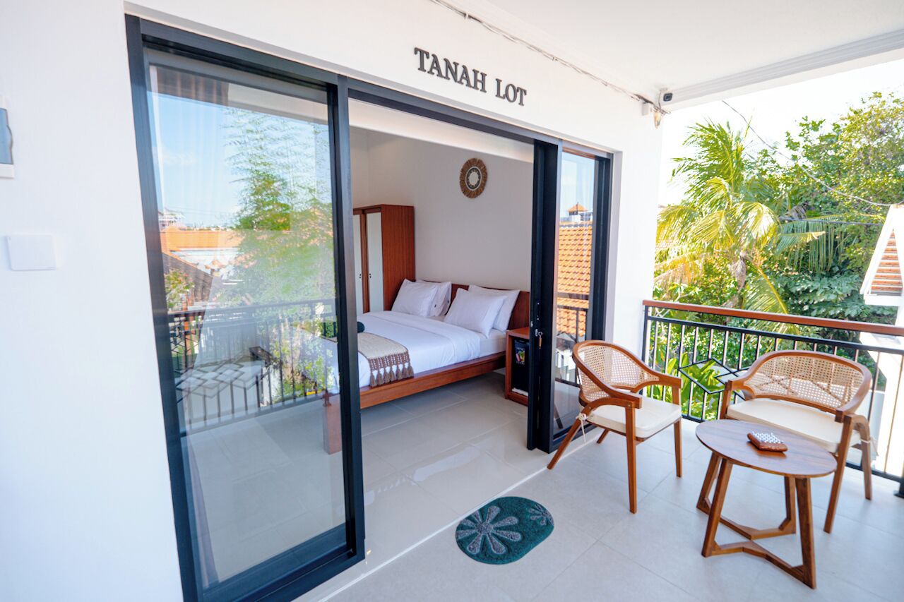 Una habitación con cama, ventana y balcón con sillas y una mesa.