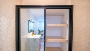 A bathroom with a marble sink, a mirror, and a shower area with wooden shelves. - Crystal Flow Guest House & Apartment Canggu (Canggu)