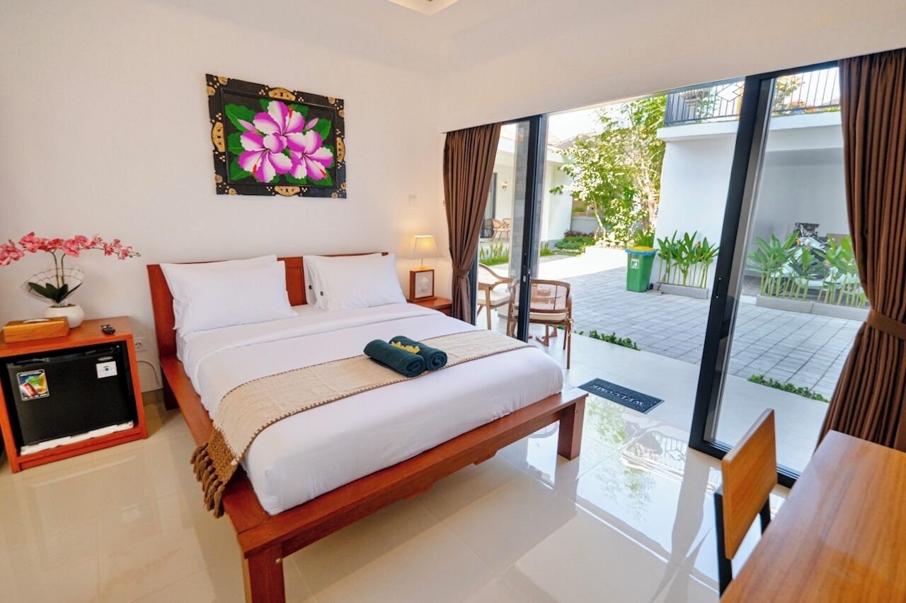 A bedroom with a bed, a bedside table, a lamp, and a view of the outdoor area.