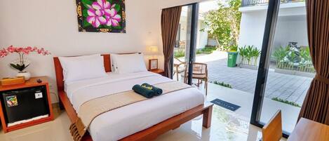 A bedroom with a bed, a bedside table, a lamp, and a view of the outdoor area.