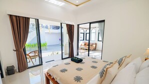 A spacious bedroom with a large bed, a bench, and a view of a balcony and outdoor seating area. - Crystal Flow Guest House & Apartment Canggu (Canggu)