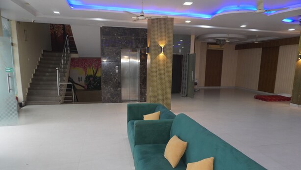 A spacious lobby with a teal sofa, a staircase, and an elevator. - Hotel Gulab Vatika (Jaipur)