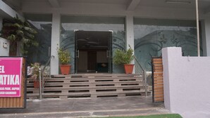 A building entrance with a staircase leading to a door, potted plants, and a signboard. - Hotel Gulab Vatika (Jaipur)