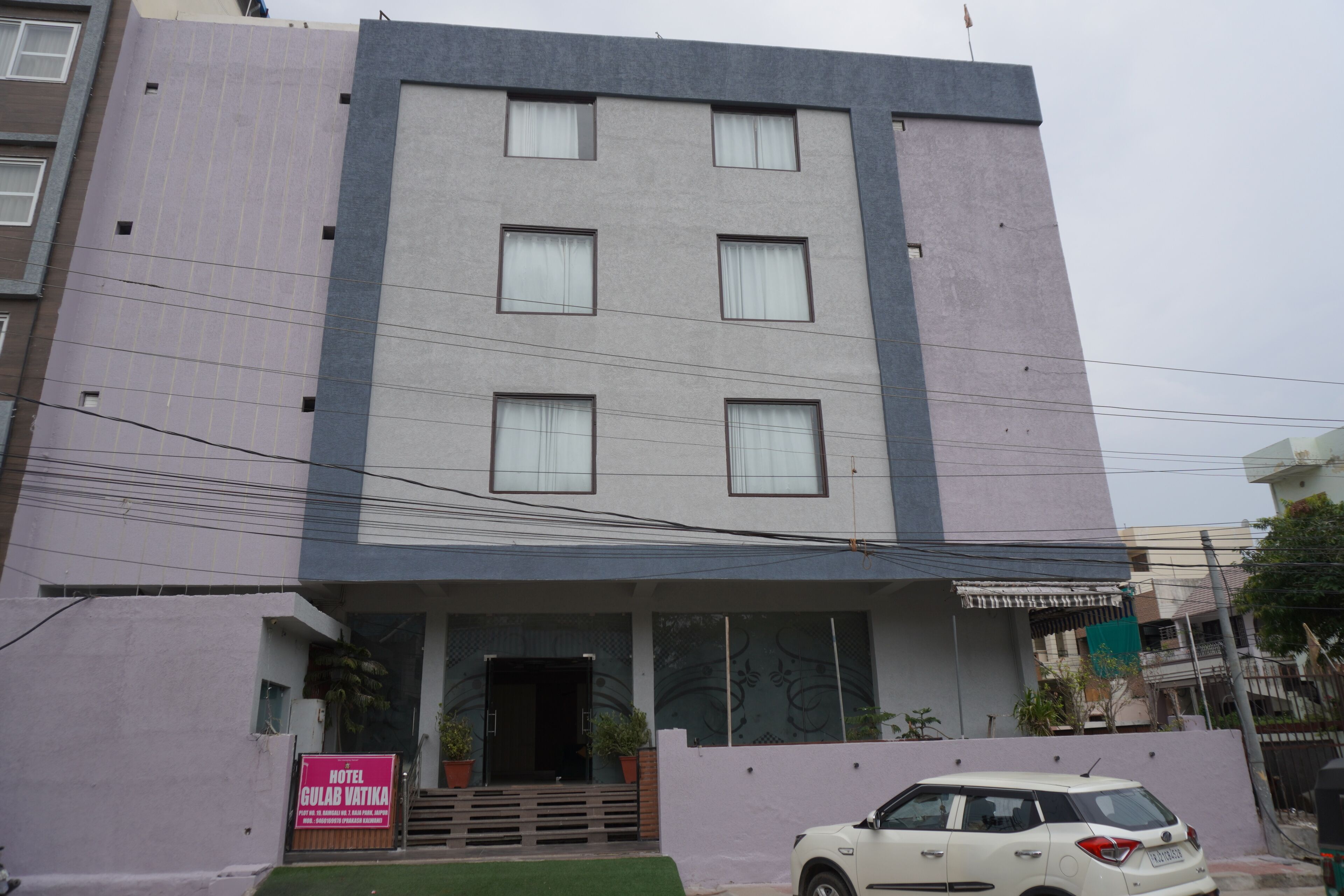 A hotel with a modern facade, a flat roof, and a signboard advertising the hotel name.