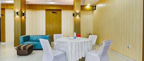 A conference room with a round table, white chairs, a sofa, and a patterned wall.