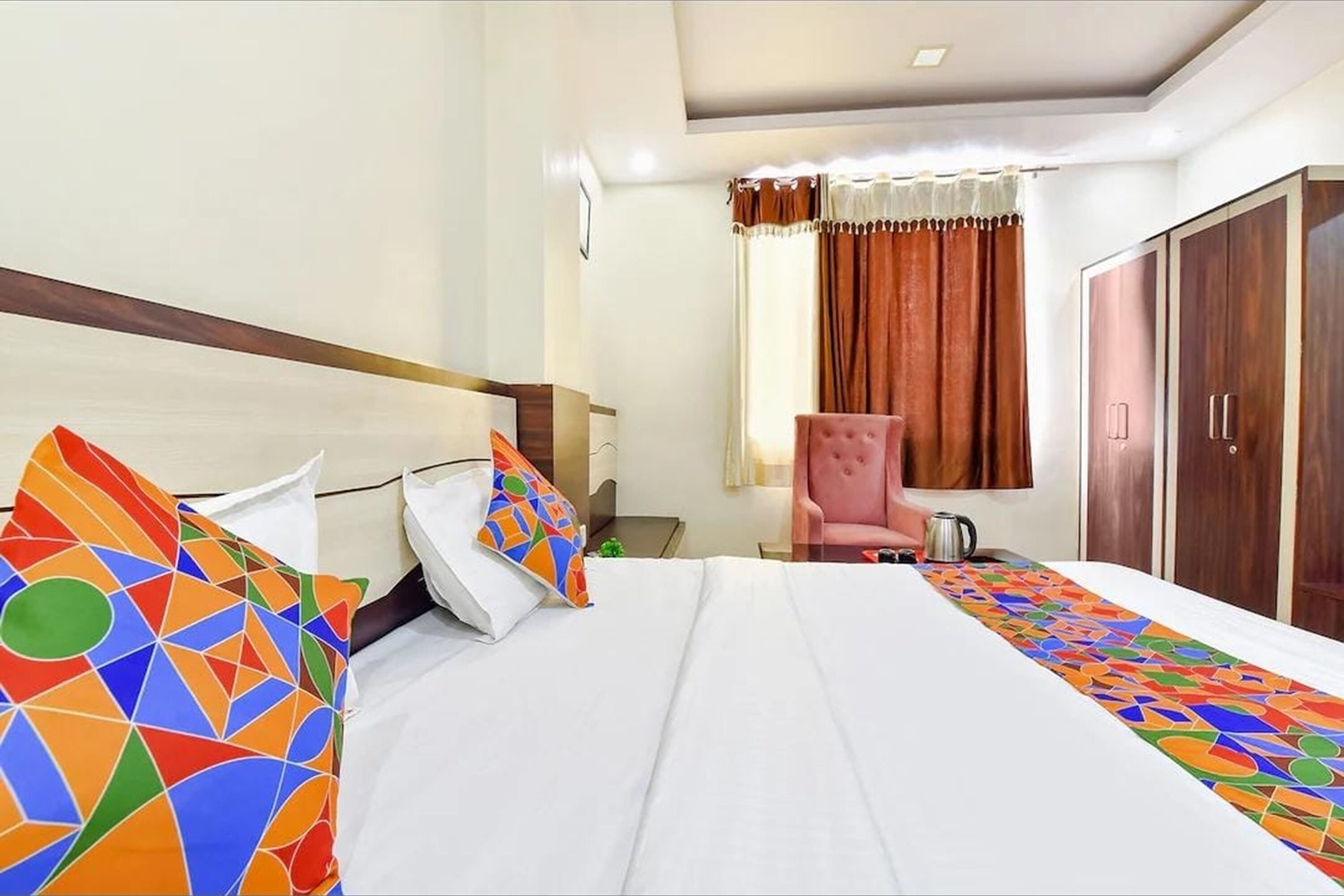 Una camera d'albergo con un letto, una sedia, un armadio e una finestra con tende.