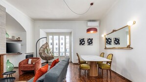 Un salon moderne avec un canapé, des fauteuils, une table à manger et des œuvres d’art accrochées aux murs.
