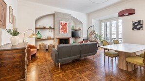 Un salon moderne comprenant un canapé, une table à manger et des chaises, un téléviseur et une cheminée.