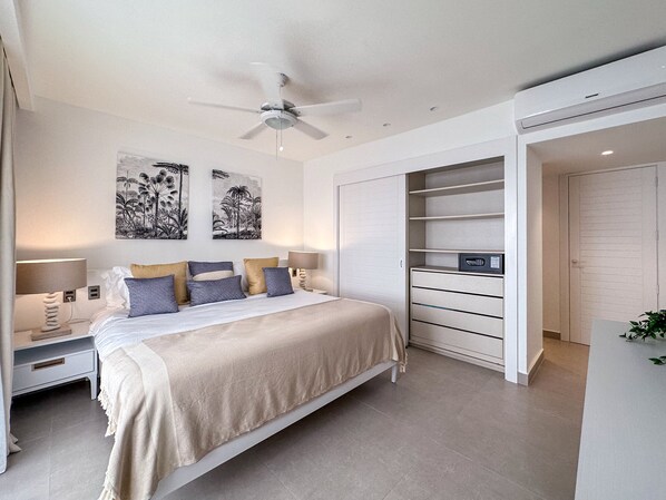 Un dormitorio moderno con cama, mesitas de noche, ventilador de techo, obras de arte y almacenamiento integrado.