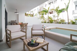 Un balcon avec une piscine, un coin salon et un barbecue.