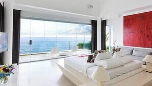 Une chambre moderne avec un grand lit, une télévision et une vue sur la mer.