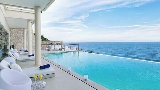 Un espace aménagé au bord de la piscine, avec des chaises longues et une vue sur l’océan.