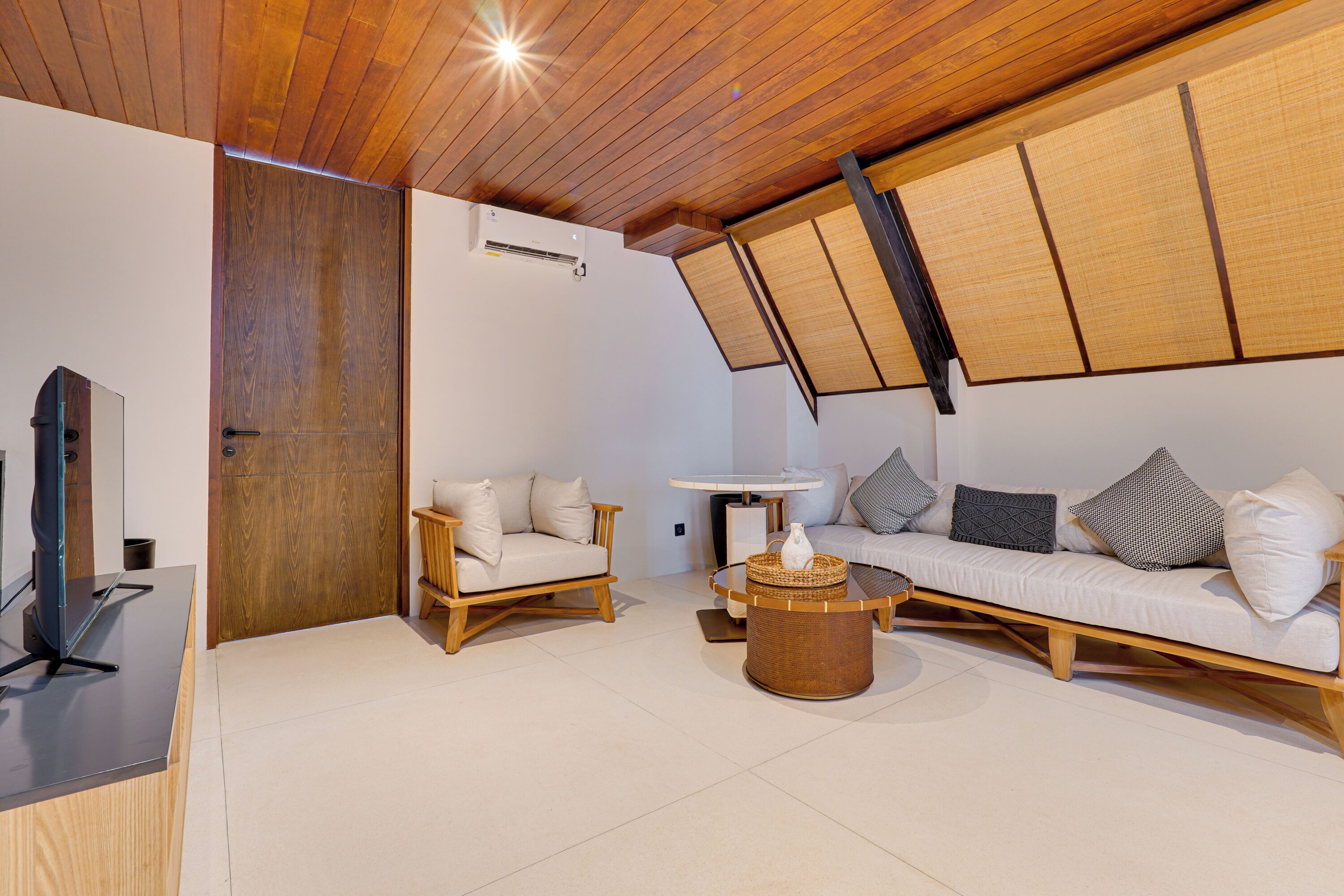 Ein modernes Wohnzimmer mit Holzboden, einer Sofagarnitur, einem Couchtisch und einem Fernseher.